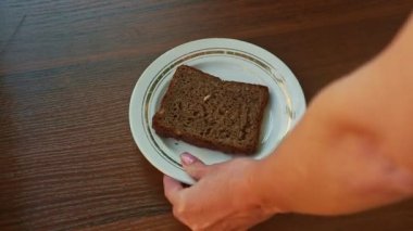 bir dilim çavdar ekmeği ile ayçiçeği tohumu ile kahverengi masa beyaz tabakta kadın el koyar