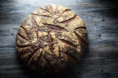 üstten görünüm büyük tamamen el yapımı yuvarlak siyah ekmek ile ilginç doku yalan üzerine koyu ahşap masa