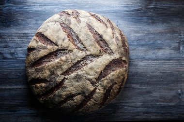 büyük tüm ev yapımı yuvarlak siyah ekmek üzerinde koyu ahşap masa ilginç doku yalanla