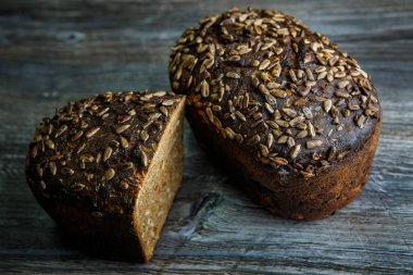 Bütün ve lezzetli el yapımı dikdörtgen çavdar ekmeği karanlık tablo arka plan ayçiçeği tohumu ile yarısı