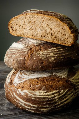 closeup bütün ve yarım adet lezzetli el yapımı dikey gri arka plan üzerinde siyah ekmek yuvarlak