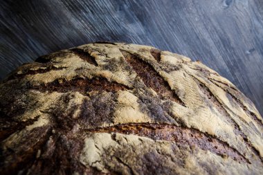 closeup büyük tamamen el yapımı yuvarlak siyah ekmek ile ilginç doku yalan üzerine koyu ahşap masa