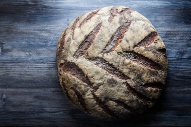 büyük tamamen el yapımı yuvarlak siyah ekmek üzerinde koyu ahşap masa ilginç doku yalanla