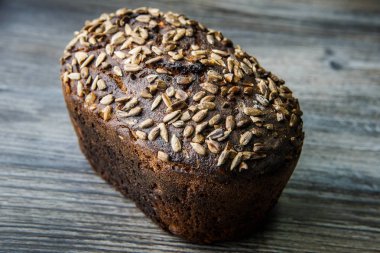 Bütün lezzetli ev yapımı dikdörtgen çavdar ekmeği ile en iyi yalan üzerine koyu ahşap arka plan ayçiçeği tohumları
