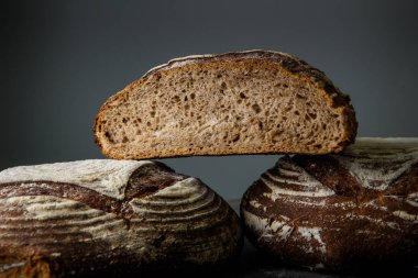 closeup üç büyük el yapımı yuvarlak siyah adet ekmek gri arka plan üzerinde