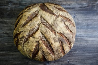 koyu ahşap masa üzerinde büyük tamamen el yapımı yuvarlak siyah ekmek ilginç doku yalanla üstten görünüm