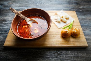 geleneksel Ukrayna Pancar çorbası sarımsak tepesi ile pişmiş halka yanındaki yeşil soğan ile dekore edilmiş ve donyağı ahşap plaka üzerine dilimlenmiş