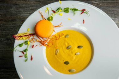 Turuncu macaron dekorasyon ahşap arka plan üzerinde derin beyaz tabakta taze kabak krem çorbası