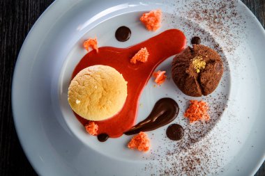 yuvarlak küçük pasta ve çikolata beyaz plaka üzerinde kırmızı vanilya sous dekorasyonu ile lezzetli tatlı