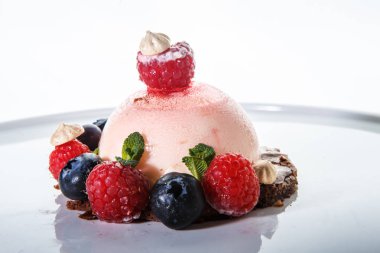 pembe tatlı taze ahududu ve beyaz arka plan beyaz bir plaka üzerinde yaban mersini ile kaplı