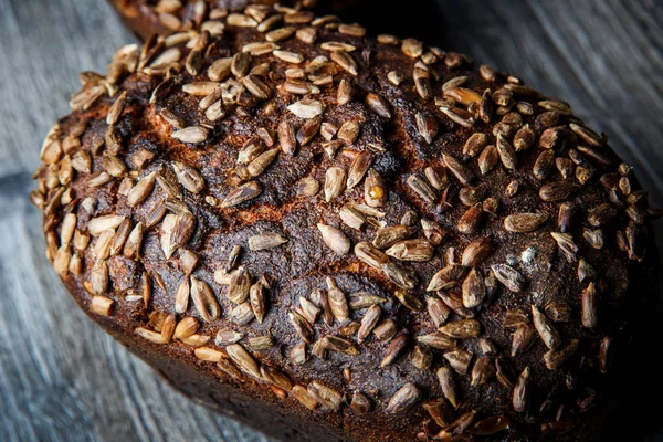 closeup whole delicious handmade rectangular rye bread with sunflower seeds on top lie on dark wooden background