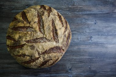 koyu ahşap masa üzerinde büyük tamamen el yapımı yuvarlak siyah ekmek ilginç doku yalanla üstten görünüm