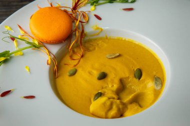 Turuncu macaron dekorasyon ahşap arka plan üzerinde derin beyaz tabakta taze kabak krem çorbası