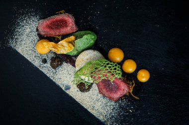 kavrulmuş et ile dekore edilmiş iki adet püresi ve siyah plaka restoran ahşap tablo üzerinde sos