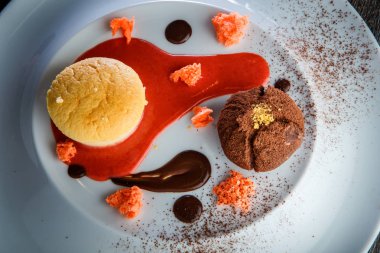 yuvarlak küçük pasta ve çikolata beyaz plaka üzerinde kırmızı vanilya sous dekorasyonu ile lezzetli tatlı