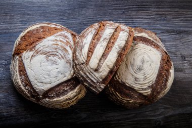 üç büyük el yapımı yuvarlak siyah parça ekmek yalan üzerine koyu ahşap masa