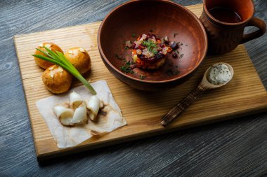 geleneksel Ukrayna plaka salata sarımsak tepesi ile pişmiş halka yanındaki yeşil soğan ile dekore edilmiş ve donyağı ahşap plaka üzerine dilimlenmiş