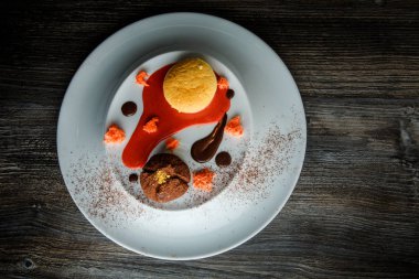 üstten görünüm lezzetli tatlı yuvarlak küçük pasta ve çikolata beyaz plaka üzerinde kırmızı vanilya sosu dekorasyonu ile