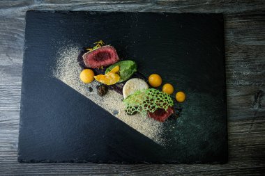 üstten görünüm üzerinde iki adet kavrulmuş et püresi ve siyah plaka restoran ahşap tablo üzerinde sos ile dekore edilmiş