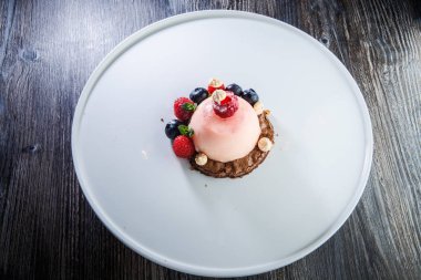 üstten görünüm üzerinde pembe tatlı taze ahududu ve ahşap masa arka plan üzerinde beyaz plaka üzerinde yaban mersini ile kaplı