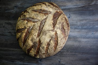 büyük tüm ev yapımı yuvarlak siyah ekmek üzerinde koyu ahşap masa ilginç doku yalanla