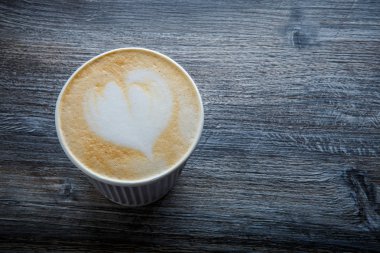 bir fincan kahve koyu ahşap masaya servis süt kalp dekorasyonu ile üzerinde üstten görünüm