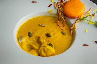 tatlı taze tohum ve turuncu acıbadem kurabiyesi dekorasyon ahşap arka plan üzerinde derin beyaz tabakta kabak krem çorbası