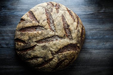 büyük tüm ev yapımı yuvarlak siyah ekmek üzerinde koyu ahşap masa ilginç doku yalanla