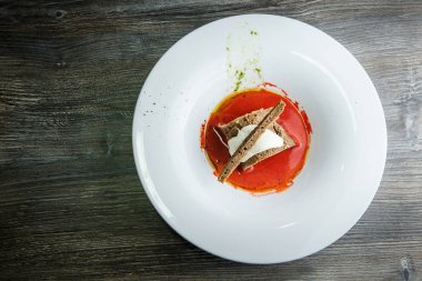 kahverengi ekmek ve koyu ahşap masa üzerinde beyaz derin kapta ekşi krema ile dekore edilmiş geleneksel Ukrayna Pancar çorbası, üstten görünüm