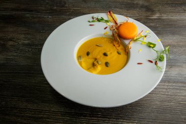 tohum ve turuncu acıbadem kurabiyesi dekorasyon ahşap arka plan üzerinde derin beyaz tabakta Taze kabak krem çorbası