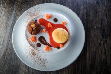 üstten görünüm lezzetli tatlı yuvarlak küçük pasta ve çikolata beyaz plaka üzerinde kırmızı vanilya sosu dekorasyonu ile