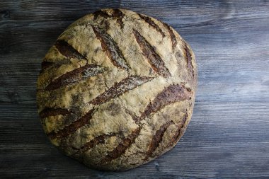 büyük tüm ev yapımı yuvarlak siyah ekmek üzerinde koyu ahşap masa ilginç doku yalanla