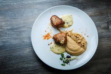 ızgara et püresi ve ahşap masa arka plan üzerinde beyaz Restoran tabakta sos ile iki lezzetli parça üzerinde üstten görünüm