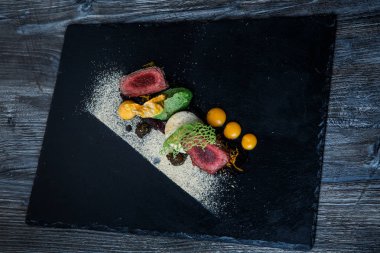 üstten görünüm üzerinde iki adet kavrulmuş et püresi ve siyah plaka restoran ahşap tablo üzerinde sos ile dekore edilmiş