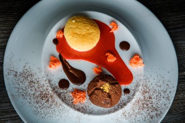 üstten görünüm lezzetli tatlı yuvarlak küçük pasta ve çikolata beyaz plaka üzerinde kırmızı vanilya sosu dekorasyonu ile