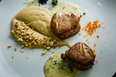 closeup iki lezzetli parçalarını ızgara et püresi ve ahşap masa arka plan üzerinde beyaz Restoran tabakta sos ile