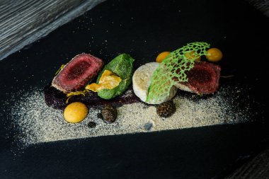 kavrulmuş et ile dekore edilmiş iki adet püresi ve siyah plaka restoran ahşap tablo üzerinde sos