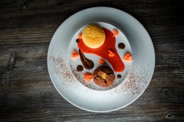 üstten görünüm lezzetli tatlı yuvarlak küçük pasta ve çikolata beyaz plaka üzerinde kırmızı vanilya sosu dekorasyonu ile