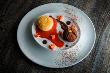 üstten görünüm lezzetli tatlı yuvarlak küçük pasta ve çikolata beyaz plaka üzerinde kırmızı vanilya sosu dekorasyonu ile