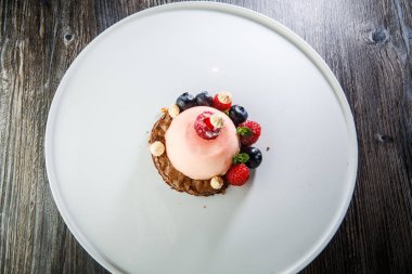 üstten görünüm üzerinde pembe tatlı taze ahududu ve ahşap masa arka plan üzerinde beyaz plaka üzerinde yaban mersini ile kaplı