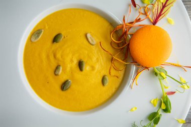 tatlı taze tohum ve turuncu acıbadem kurabiyesi dekorasyon ahşap arka plan üzerinde derin beyaz tabakta kabak krem çorbası