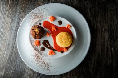 üstten görünüm lezzetli tatlı yuvarlak küçük pasta ve çikolata beyaz plaka üzerinde kırmızı vanilya sosu dekorasyonu ile