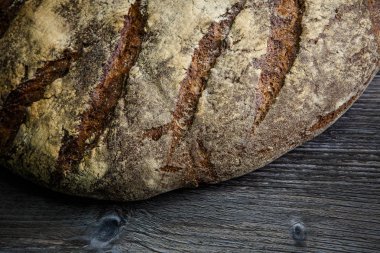 closeup büyük tamamen el yapımı yuvarlak siyah ekmek ile ilginç doku yalan üzerine koyu ahşap masa