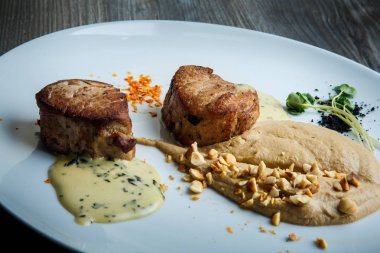 closeup iki lezzetli parçalarını ızgara et püresi ve ahşap masa arka plan üzerinde beyaz Restoran tabakta sos ile