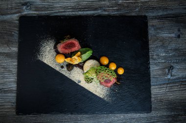 üstten görünüm üzerinde iki adet kavrulmuş et püresi ve siyah plaka restoran ahşap tablo üzerinde sos ile dekore edilmiş