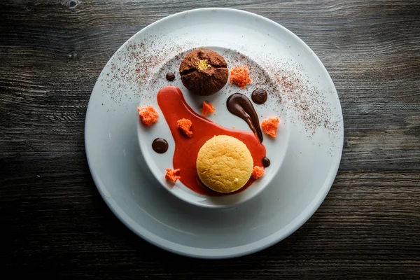 üstten görünüm lezzetli tatlı yuvarlak küçük pasta ve çikolata beyaz plaka üzerinde kırmızı vanilya sosu dekorasyonu ile