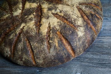 closeup büyük tamamen el yapımı yuvarlak siyah ekmek ile ilginç doku yalan üzerine koyu ahşap masa