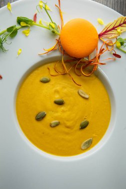 tatlı taze tohum ve turuncu acıbadem kurabiyesi dekorasyon ahşap arka plan üzerinde derin beyaz tabakta kabak krem çorbası