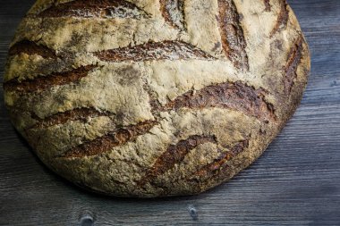 closeup büyük tamamen el yapımı yuvarlak siyah ekmek ile ilginç doku yalan üzerine koyu ahşap masa