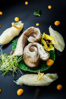 patates püresi ve Restoran siyah plaka üzerinde sarı sostan closeup iki lezzetli balık parçalarını süslenmiş